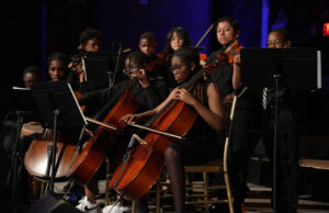 Students playing string instruments on stage