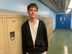 high school student posing in student hallway against lockers