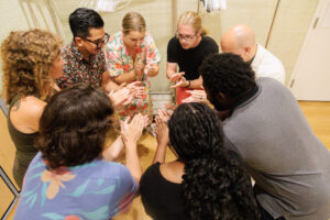 group of adult teachers putting their hands together as a team